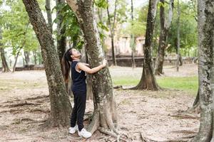 jonge vrouw knuffelen een grote boom, hou van natuur concept. foto