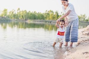 een jonge moeder speelt in de zomer met haar 2-5 jaar oude dochter op het strand. buitenresort aan het meer heerlijk uitrusten in het weekend, familiedagen. foto