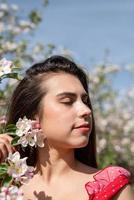 jonge blanke vrouw die geniet van de bloei van een appelboom foto