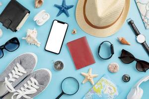 bovenaanzicht reisaccessoires met schoenen, kaart, smartphone met mockup-scherm, hoed. toeristische benodigdheden. foto