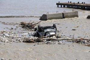 beschadigde auto aan de kust na een natuurramp, een bergrivier spoelde de auto de zee in. foto