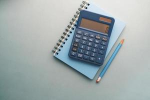bovenaanzicht van blauwe rekenmachine en notitieblok op gekleurde achtergrond foto