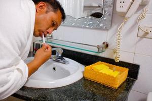 man tandenborstel schone tanden in de badkamer. knappe man zijn tanden poetsen in de ochtend in de badkamer. gelukkige man bij het tandenpoetsen voordat hij gaat slapen. foto