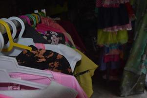 kleren die in de winkel hangen met een donkere kamerachtergrond foto