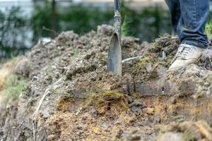 tuinman graaft de grond met zijn uitrusting om te tuinieren en maakt land klaar voor plantage. foto