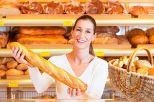vrouwelijke bakker in haar bakkerij met stokbrood foto
