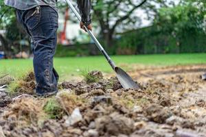 tuinman graaft de grond met zijn uitrusting om te tuinieren en maakt land klaar voor plantage. foto
