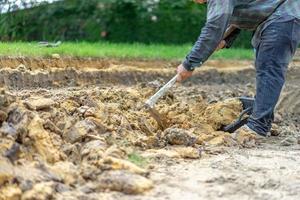 tuinman graaft de grond met zijn uitrusting om te tuinieren en maakt land klaar voor plantage. foto