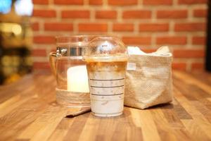take away latte met bakstenen achtergrond op de houten tafel foto