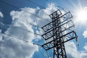 hoogspannings elektrische transmissie hoektoren tegen de achtergrond van een bewolkte hemel met zonnestralen. foto