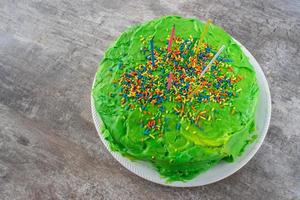 heldergroene kleurrijke zelfgemaakte cake met kaarsen en hagelslag bovenaanzicht foto