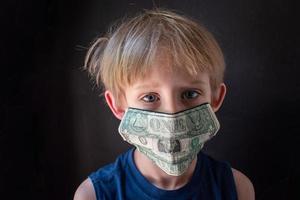 de echte kosten van een pandemie met een medisch masker gemaakt van geld op het gezicht van een kind foto