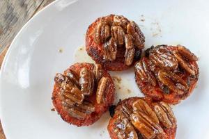 gebakken oranje zoete aardappel of yam rondjes gegarneerd met gekarameliseerde pecannoten foto