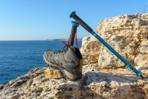 olijfgroene wandelschoenen op een natuurlijke achtergrond van zee en rotsen foto