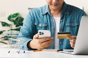 zakenman hand met creditcard met het gebruik van smartphone voor online winkelen terwijl het maken van bestellingen thuis. business, lifestyle, technologie, e-commerce, digitaal bankieren en online betalingsconcept. foto