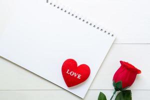 presenteren rode roos bloem en notebook en hart vorm met kopie ruimte op houten tafel, 14 februari van liefdesdag met romantisch, valentijn vakantieconcept. foto