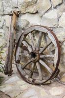 oud houten en metalen wiel op stenen muur foto
