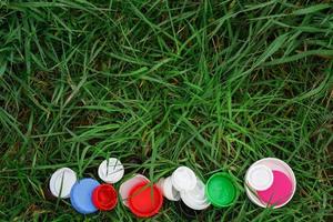 kleurrijke plastic kroonkurken op het groene gras. vrijwilligers liefdadigheidsevenement goede deksels om weeskinderen te helpen. foto