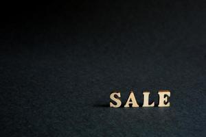 inscriptie verkoop van houten letters op een zwarte achtergrond. zwarte vrijdag, kortingen, verkoop, winkelen, renteteken. ruimte voor tekst foto