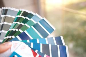 selectie van de verfkleur voor decoratieve huisreparaties aan het palet met lay-outs. een waaier van tinten in je hand in huis. reparatie en constructie, verf- en lakcoating foto