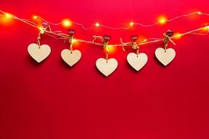 slinger van houten harten met wasknijpers met de inscriptie liefde op een rode achtergrond. Valentijnsdag, kopieer ruimte, bespotten. vakantielichten, flyer, geliefden foto
