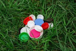 kleurrijke plastic kroonkurken op het groene gras. vrijwilligers liefdadigheidsevenement goede deksels om weeskinderen te helpen. foto