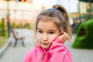 een klein meisje met een verdrietig en bang gezicht houdt haar wang vast met haar hand - een tand doet pijn. oorpijn, kiespijn, gezwollen wangen en tandvlees, problemen van pediatrische tandheelkunde, KNO. kindergeneeskunde foto