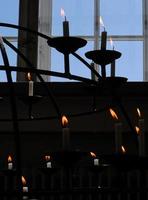 contrast van lichte en donkere kaarslichten op kandelaar in de kerk met blauwe hemelachtergrond foto