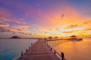 zonsondergang op het eiland Malediven, luxe watervilla's resort en houten pier. mooie lucht en wolken en strandachtergrond voor de zomervakantie en reisconcept foto