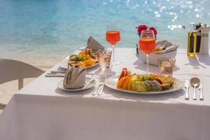 luxe ontbijt eten op witte tafel, met prachtige tropische zeezicht achtergrond, ochtend tijd zomervakantie en romantisch vakantie concept, luxe reizen en lifestyle foto
