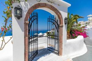 ingang van een typische witte Cycladische architectuur, huis met blauwe deur en bloeiende roze bougainvillea plant in santorini eiland griekenland. inspirerende idyllische romantische reisvakantie achtergrond foto