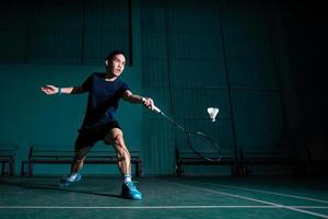 professionele badmintonspeler gebruikt racket hit shuttle cock of shuttle op de baan tijdens warming-up spelen voor toernooi competitie in single man type in indoor court foto