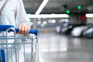 gelukkige vrouw vrouw met close-up winkelwagentje of trolley in auto parkeren van verse maket voor gezonde huisvrouw in supermarkt winkel foto