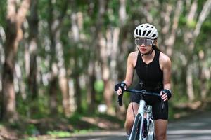 gelukkige vrouw fietsatleet bereidt zich voor op fietsen op straat, op de weg, met hoge snelheid voor oefenhobby en competitie in professionele tour