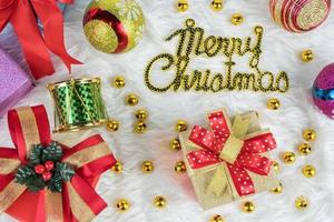 merry christmas achtergrond gouden geschenkdoos met rode linten en versieringen op witte nerts katoenen achtergrond. bovenaanzicht.viering kerstfestival foto