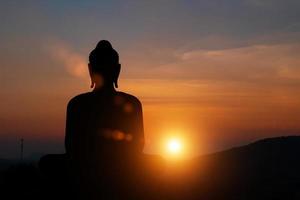 silhouet van Boeddhabeeld bij zonsondergang hemelachtergrond. boeddhistische heilige dagen concept. foto