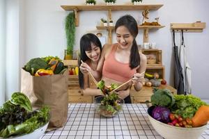 Aziatisch koppel van hetzelfde geslacht huwelijk samen gezonde salade koken in de keuken tijdens de trotsmaand om gelijkheid en verschillen van homoseksueel en discriminatieconcept te bevorderen foto