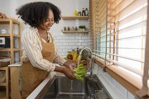 Afro-Amerikaanse huisvrouw maakt groene sla schoon om een eenvoudige en gemakkelijke salademaaltijd in zuidelijke stijl te bereiden voor veganistisch en vegetarisch voedselconcept foto