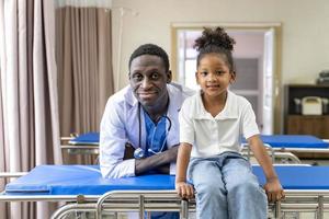 Afro-Amerikaanse arts en kind patiënt portret op de afspraak van de ziekenhuiskliniek voor diagnose en medische controle foto