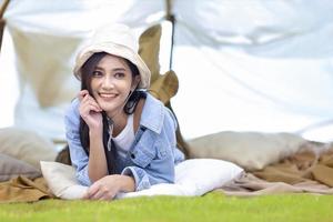 Aziatische vrouw blijft in haar tent terwijl ze in de zomer buiten kampeert in het nationaal park voor avontuur en actief reisconcept foto