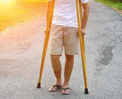 de afbeelding toont patiënten met enkelblessures met bandages enkelbrace en krukken gebruiken om het lopen op het gazon te ondersteunen. gezondheidszorg en medisch concept. foto