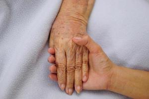 aanraken of hand in hand senior of oudere oude vrouw op een blauwe doek met liefde, zorg aanmoedigen en empathie. foto