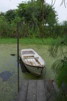 natuurlijk meerlandschap met witte kleine vissersboot naar de houten pier foto