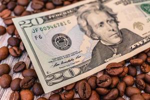 een bankbiljet ligt op de korrels van gebrande koffie, symboliseert de prijsstijging of verlaging van de kosten van natuurlijke koffie. twintig dollar liggen op korrels natuurlijke koffie foto