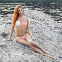 sexy meisje met rood haar in een bikini op het strand. foto