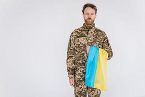 Oekraïense patriot soldaat in militair uniform met een gele en blauwe vlag op een witte achtergrond foto