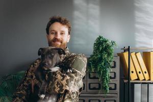 portret van een Oekraïense soldaat en zijn trouwe vriend de amstaff-hond op kantoor foto