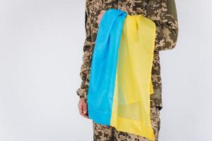 Oekraïense patriot soldaat in militair uniform met een gele en blauwe vlag op een witte achtergrond foto