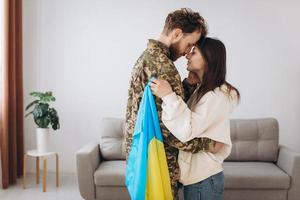 een oekraïens meisje knuffelt en houdt een gele en blauwe vlag van een militair in uniform vast en neemt afscheid van hem. foto