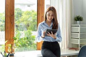 creatieve aziatische jonge vrouw die aan tablet in haar studio werkt. foto